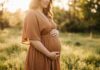 Nurturing Life: A Comprehensive Guide to Special Care During Pregnancy A pregnant woman standing in a sunlit field at sunset, gently holding her belly.